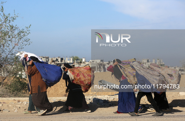 Palestinian Bedouin women carry their belongings as they walk along Salah al-Din Street in Deir Al-Balah in the central Gaza Strip on Novemb...