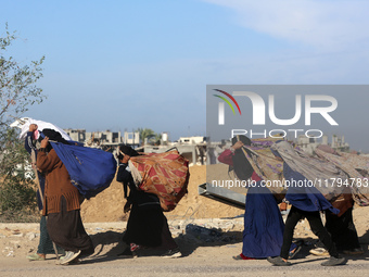 Palestinian Bedouin women carry their belongings as they walk along Salah al-Din Street in Deir Al-Balah in the central Gaza Strip on Novemb...