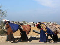 Palestinian Bedouin women carry their belongings as they walk along Salah al-Din Street in Deir Al-Balah in the central Gaza Strip on Novemb...