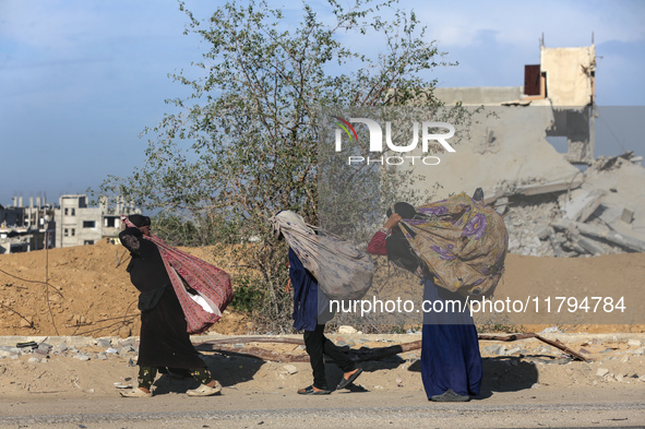 Palestinian Bedouin women carry their belongings as they walk along Salah al-Din Street in Deir Al-Balah in the central Gaza Strip on Novemb...