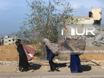 Palestinian Bedouin women carry their belongings as they walk along Salah al-Din Street in Deir Al-Balah in the central Gaza Strip on Novemb...