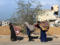 Palestinian Bedouin women carry their belongings as they walk along Salah al-Din Street in Deir Al-Balah in the central Gaza Strip on Novemb...