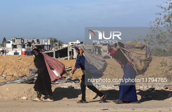 Palestinian Bedouin women carry their belongings as they walk along Salah al-Din Street in Deir Al-Balah in the central Gaza Strip on Novemb...