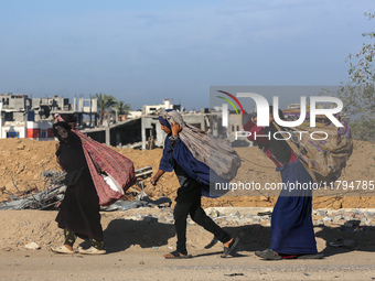 Palestinian Bedouin women carry their belongings as they walk along Salah al-Din Street in Deir Al-Balah in the central Gaza Strip on Novemb...