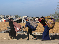 Palestinian Bedouin women carry their belongings as they walk along Salah al-Din Street in Deir Al-Balah in the central Gaza Strip on Novemb...