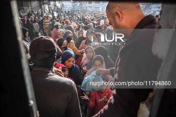 Palestinians wait in a queue to receive bread outside a bakery in Khan Yunis, on November 20, 2024, amid the ongoing war between Israel and...