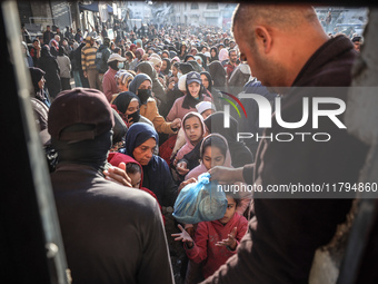 Palestinians wait in a queue to receive bread outside a bakery in Khan Yunis, on November 20, 2024, amid the ongoing war between Israel and...