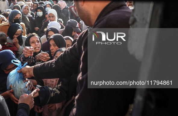 Palestinians wait in a queue to receive bread outside a bakery in Khan Yunis, on November 20, 2024, amid the ongoing war between Israel and...