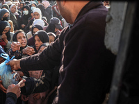 Palestinians wait in a queue to receive bread outside a bakery in Khan Yunis, on November 20, 2024, amid the ongoing war between Israel and...