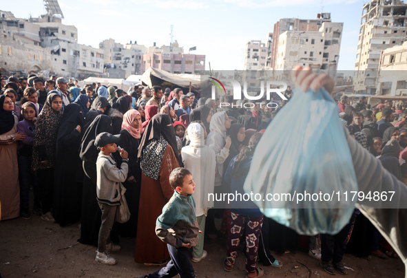 Palestinians wait in a queue to receive bread outside a bakery in Khan Yunis, on November 20, 2024, amid the ongoing war between Israel and...