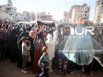 Palestinians wait in a queue to receive bread outside a bakery in Khan Yunis, on November 20, 2024, amid the ongoing war between Israel and...