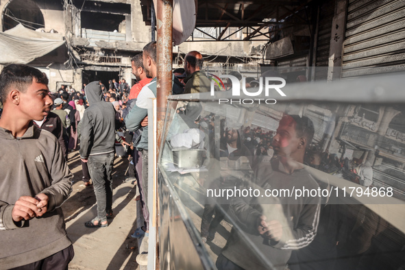 Palestinians wait in a queue to receive bread outside a bakery in Khan Yunis, on November 20, 2024, amid the ongoing war between Israel and...