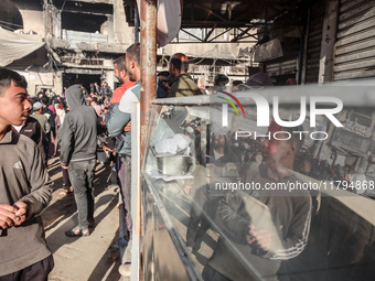 Palestinians wait in a queue to receive bread outside a bakery in Khan Yunis, on November 20, 2024, amid the ongoing war between Israel and...