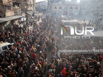 Palestinians wait in a queue to receive bread outside a bakery in Khan Yunis, on November 20, 2024, amid the ongoing war between Israel and...