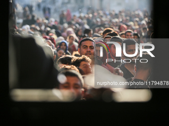 Palestinians wait in a queue to receive bread outside a bakery in Khan Yunis, on November 20, 2024, amid the ongoing war between Israel and...