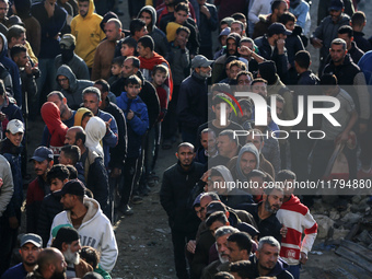 Palestinians wait in a queue to receive bread outside a bakery in Khan Yunis, on November 20, 2024, amid the ongoing war between Israel and...