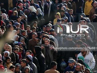 Palestinians wait in a queue to receive bread outside a bakery in Khan Yunis, on November 20, 2024, amid the ongoing war between Israel and...