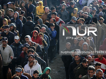 Palestinians wait in a queue to receive bread outside a bakery in Khan Yunis, on November 20, 2024, amid the ongoing war between Israel and...