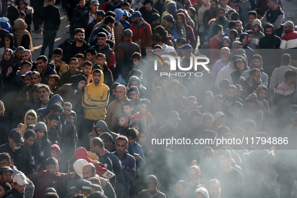 Palestinians wait in a queue to receive bread outside a bakery in Khan Yunis, on November 20, 2024, amid the ongoing war between Israel and...