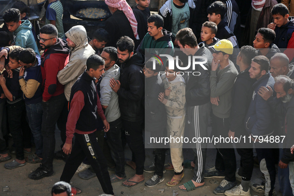 Palestinians wait in a queue to receive bread outside a bakery in Khan Yunis, on November 20, 2024, amid the ongoing war between Israel and...