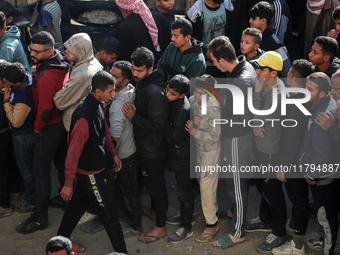 Palestinians wait in a queue to receive bread outside a bakery in Khan Yunis, on November 20, 2024, amid the ongoing war between Israel and...