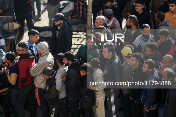 Palestinians wait in a queue to receive bread outside a bakery in Khan Yunis, on November 20, 2024, amid the ongoing war between Israel and...