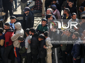 Palestinians wait in a queue to receive bread outside a bakery in Khan Yunis, on November 20, 2024, amid the ongoing war between Israel and...