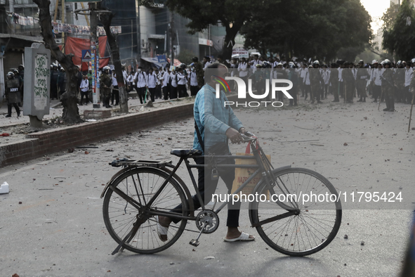 Commuters pass by a road during a clash in Dhaka, Bangladesh, on November 20, 2024. 