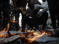 A commuter inhales fire smoke to counteract tear gas during a clash in Dhaka, Bangladesh, on November 20, 2024. (