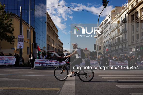 A cyclist passes in front of workers' blocs during the pre-rallies for the nationwide general strike in Athens, Greece, on November 20, 2024...