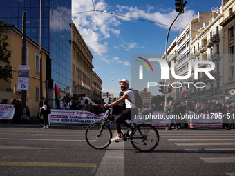 A cyclist passes in front of workers' blocs during the pre-rallies for the nationwide general strike in Athens, Greece, on November 20, 2024...