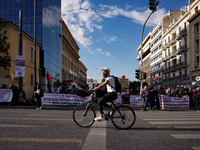 A cyclist passes in front of workers' blocs during the pre-rallies for the nationwide general strike in Athens, Greece, on November 20, 2024...