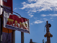 The logo of the All-Workers Militant Front (PAME) is displayed with the statue of the goddess Athena at the University of Athens in the back...