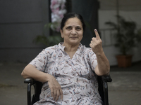 An Indian voter poses with her inked finger after casting her ballot during the Maharashtra state assembly elections at a polling booth in M...