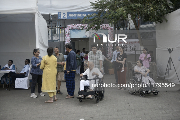 Indian voters in a wheelchair come out after casting their ballot during the Maharashtra state assembly elections at a polling booth in Mumb...