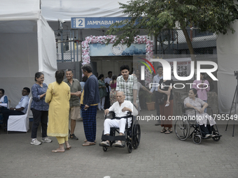 Indian voters in a wheelchair come out after casting their ballot during the Maharashtra state assembly elections at a polling booth in Mumb...