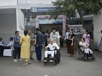 Indian voters in a wheelchair come out after casting their ballot during the Maharashtra state assembly elections at a polling booth in Mumb...