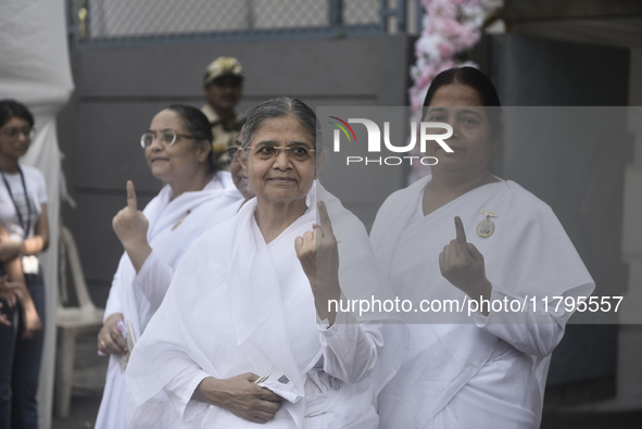 Brahma Kumari sisters pose with their inked fingers after casting their ballots during the Maharashtra state assembly elections at a polling...