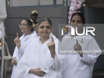 Brahma Kumari sisters pose with their inked fingers after casting their ballots during the Maharashtra state assembly elections at a polling...