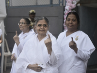 Brahma Kumari sisters pose with their inked fingers after casting their ballots during the Maharashtra state assembly elections at a polling...