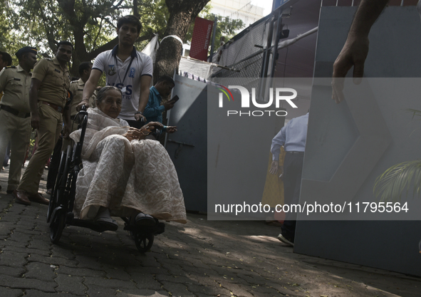 An old woman in a wheelchair comes out after casting her ballot to vote during the Maharashtra state assembly elections at a polling booth i...