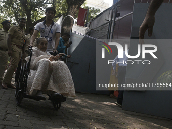 An old woman in a wheelchair comes out after casting her ballot to vote during the Maharashtra state assembly elections at a polling booth i...