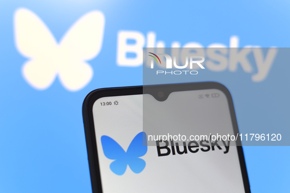 The logo of the social network Bluesky appears on the screen of a smartphone and on the computer screen in the background in Reno, United St...