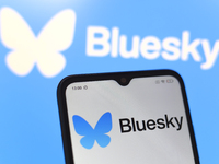 The logo of the social network Bluesky appears on the screen of a smartphone and on the computer screen in the background in Reno, United St...