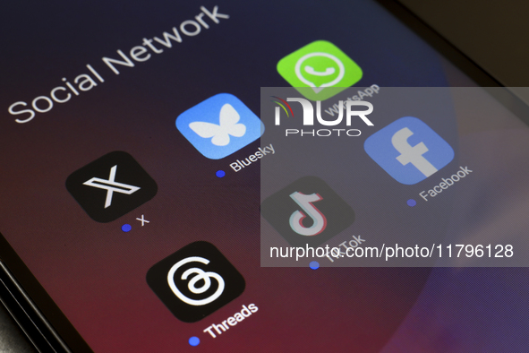 The logos of the social networks X (Twitter), Bluesky, WhatsApp, Threads, TikTok, and Facebook are displayed on the screen of a smartphone i...