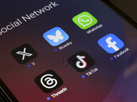 The logos of the social networks X (Twitter), Bluesky, WhatsApp, Threads, TikTok, and Facebook are displayed on the screen of a smartphone i...