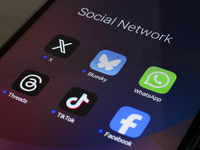 The logos of the social networks X (Twitter), Bluesky, WhatsApp, Threads, TikTok, and Facebook are displayed on the screen of a smartphone i...