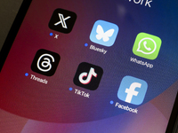 The logos of the social networks X (Twitter), Bluesky, WhatsApp, Threads, TikTok, and Facebook are displayed on the screen of a smartphone i...