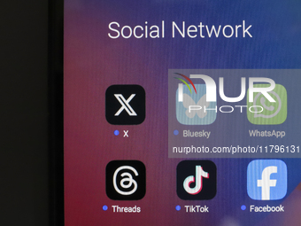 The logos of the social networks X (Twitter), Bluesky, WhatsApp, Threads, TikTok, and Facebook are displayed on the screen of a smartphone i...