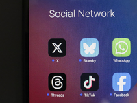 The logos of the social networks X (Twitter), Bluesky, WhatsApp, Threads, TikTok, and Facebook are displayed on the screen of a smartphone i...